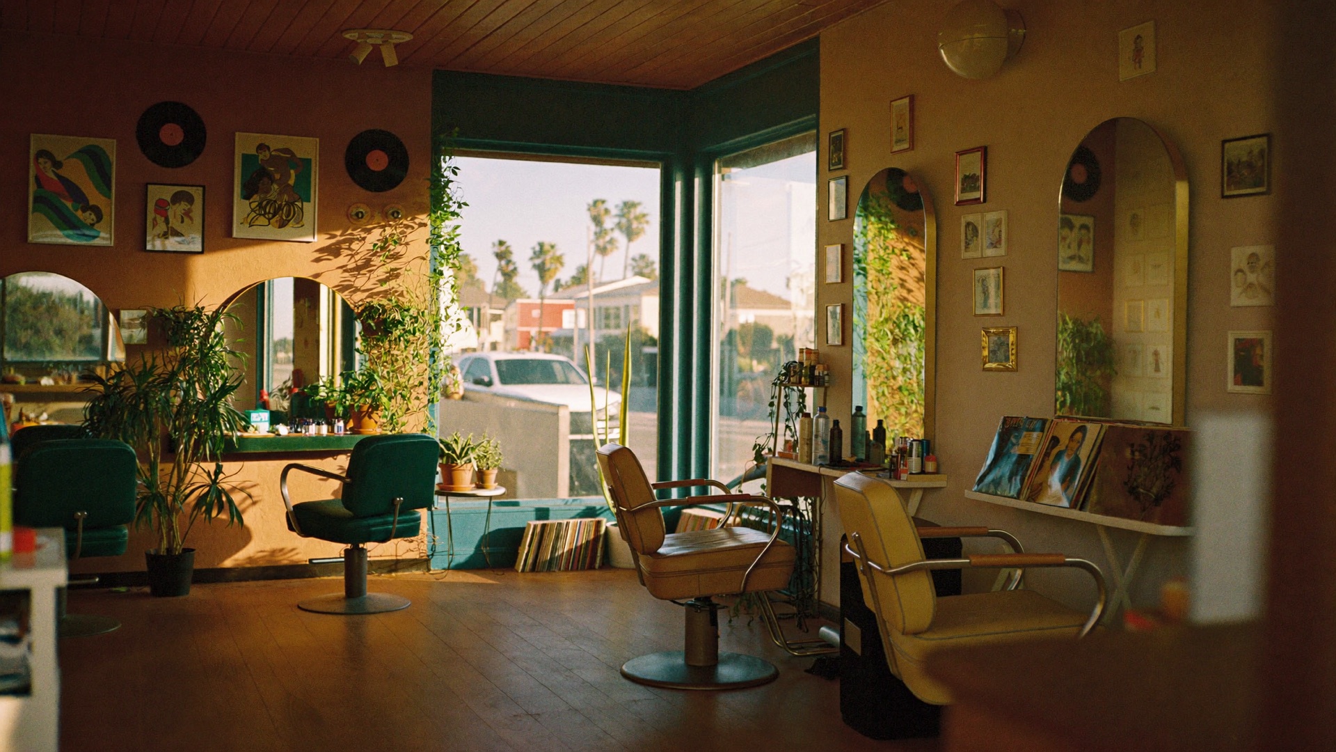The warm, plant-filled interior of Pleasure Head Salon at golden hour — vintage chairs, arched mirrors and records on the walls